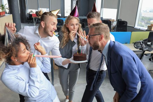 Happy business team with birthday cake are greeting colleague at office party.