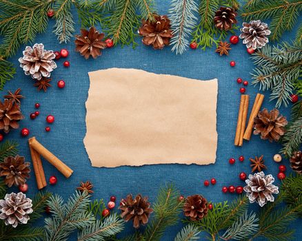 Christmas and Happy New Year dark blue background with craft paper for text. Frame for recipe, menu with fir branches, cones, cranberry berries. Textile backdrop with copy space.