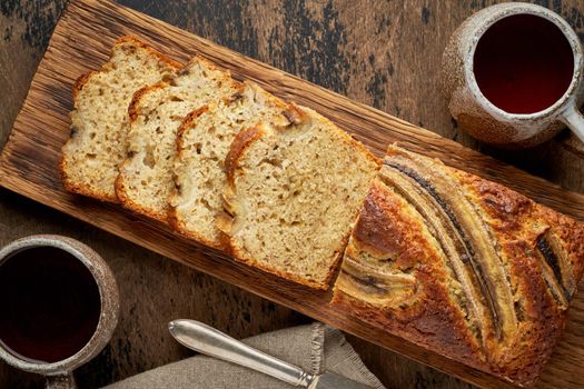 Banana bread. Cake with banana, traditional american cuisine. Slices of loaf. Dark background, black table.
