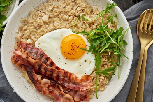 Oatmeal, fried egg and fried bacon. Brutal man sport breakfast. Hearty fat high-calorie breakfast, source of energy. Balance of proteins, fats, carbohydrates. Balanced food.