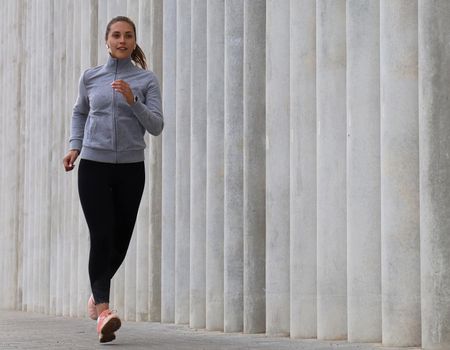 Attractive young sporty woman in full length running outdoor.
