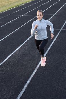 Runner athlete running on athletic track training her cardio in stadium. Jogging at fast pace for competition.