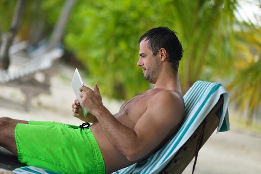 business man relaxing and use tablet computer at beautiful tropical beach