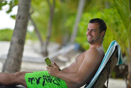 business man relaxing and use tablet computer at beautiful tropical beach