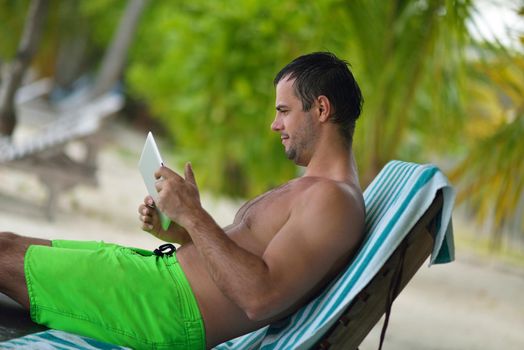 business man relaxing and use tablet computer at beautiful tropical beach