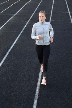 Runner athlete running on athletic track training her cardio in stadium. Jogging at fast pace for competition.