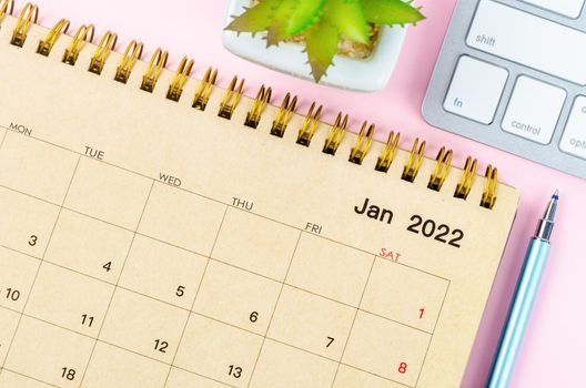 January 2022 desk calendar with keyboard computer on pink background.