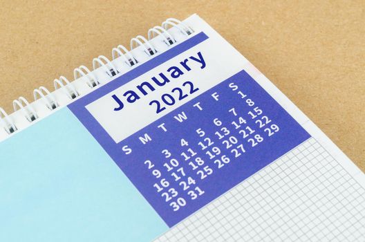 Close up January 2022 desk calendar on brown background.