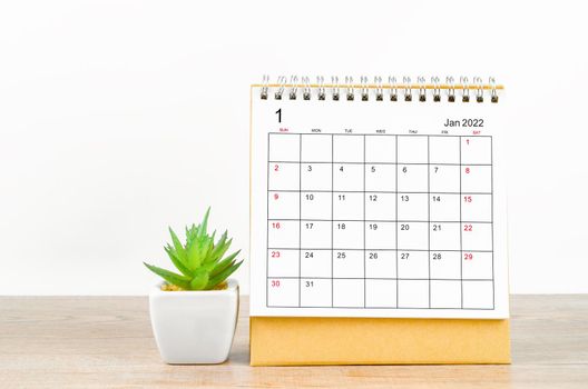 January 2022 desk calendar with plant pot on wooden table.
