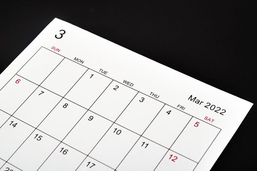 Close up March 2022 calendar sheet on black background.