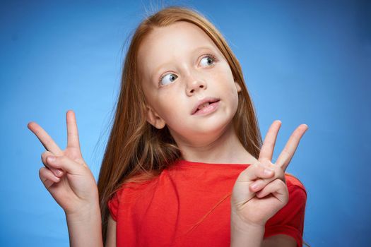 cute red-haired girl in red t-shirt emotions blue background. High quality photo