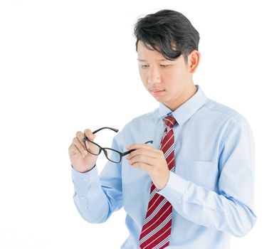 Male wearing blue shirt and red tie holding eyeglasses isolated on white background