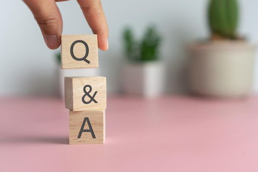 Q and A alphabet on wooden cube in hand hold with background. Question and answer meaning concept.