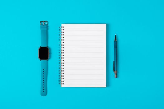 Notepad, watch, pen isolated on light blue background. Notepad with copy space. Office, business, discreet style