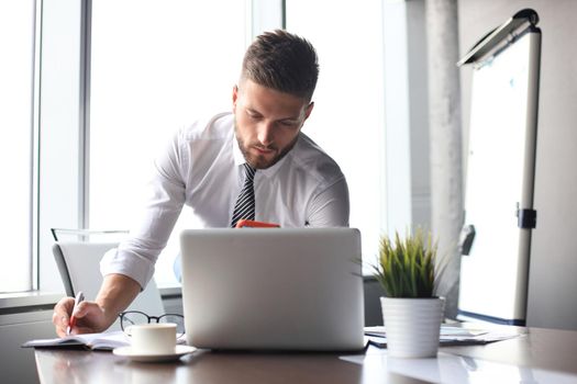 Portrait of happy businessman sitting at office desk.