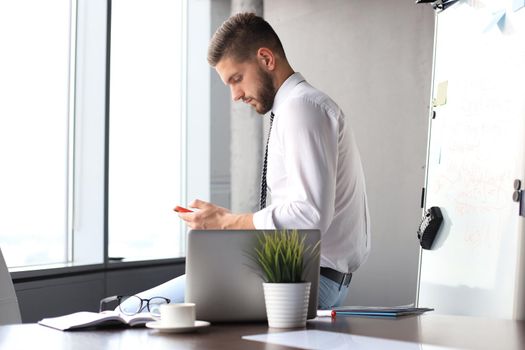 Portrait of happy businessman sitting on office desk.