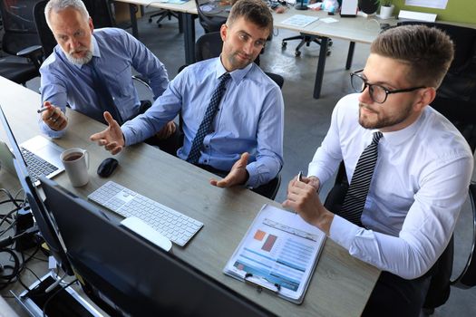 Group of young business men in formalwear working using computers while sitting in the office