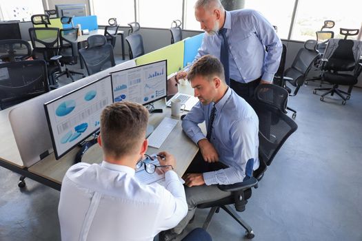 Group of young business men in formalwear working using computers while sitting in the office