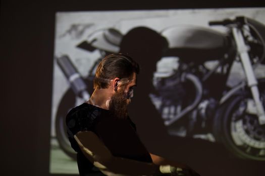 male biker standing in the background of the photo of his motorcycle.the concept of a hobby
