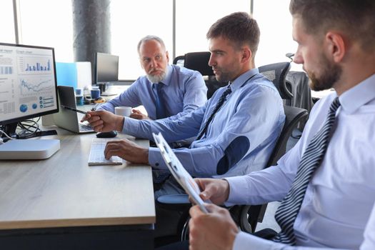 Group of young business men in formalwear working using computers while sitting in the office