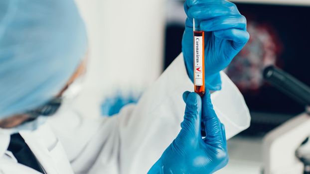 close up. tube with a tested test in the hands of a virologist. photo with a copy-space.