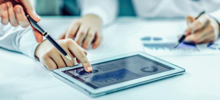 closeup of businessman using digital tablet, working with the financial schedule at the Desk .the photo has a empty space for your text