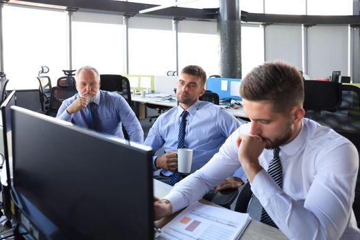 Group of young business men in formalwear working using computers while sitting in the office