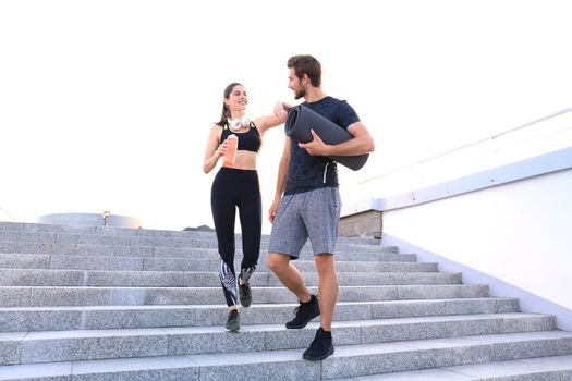 Young couple in sportswear going down the stairs after exercising outdoors