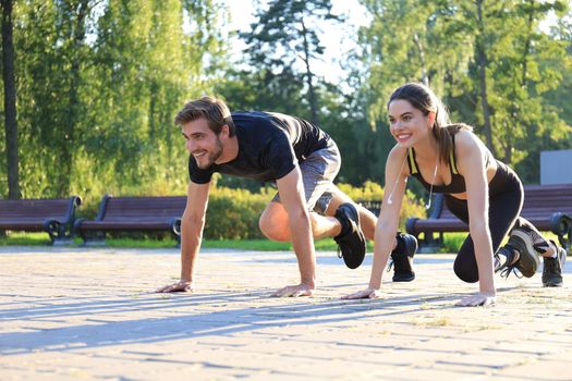 Young couple doing exercise together while working out outdoors in park