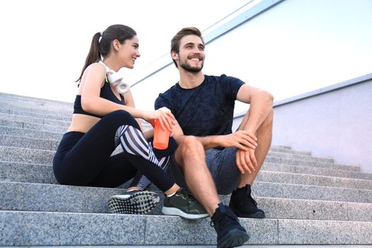 Young couple in sportswear sitting on the stairs after exercising outdoors