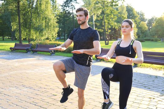 Young couple doing exercise together while working out outdoors in park