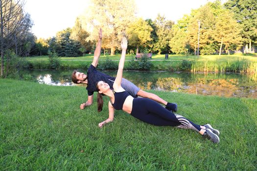 Young couple doing exercise together while working out outdoors in park