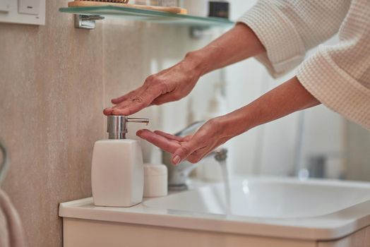 Woman hands using soap dispenser standing on basin at bathroom. Beauty, skincare and cosmetology concept