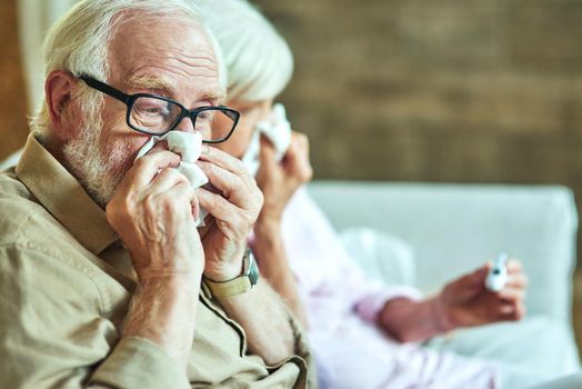 Cropped senior man in glasses sitting next to his wife and having a runny nose. Care and health concept. Copy space