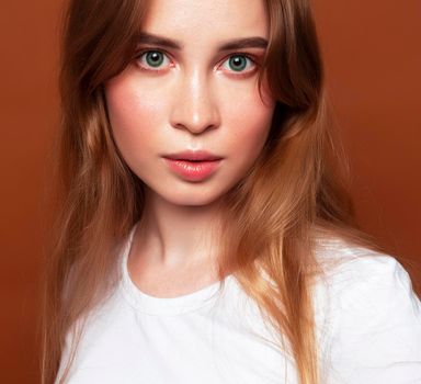 young pretty girl with blond hair posing cheerful on brown background, lifestyle people concept close up