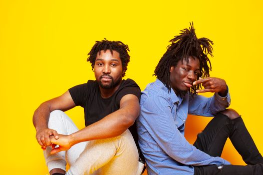 two african american guys posing cheerful together on yellow background, lifestyle people concept close up