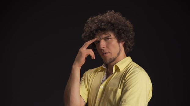 Serious thoughtful man generates idea while touching his forehead with fingers. Isolated on black background. High quality photo.