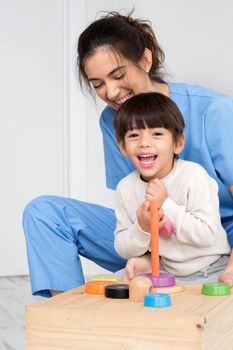 Physical therapist playing with a boy who has cerebral palsy. High quality photo.