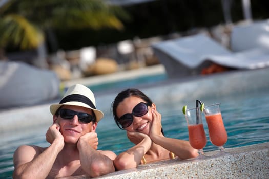 happy young couple relax and take fresh drink at summer vacation on swimmin pool