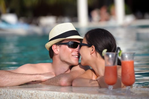 happy young couple relax and take fresh drink at summer vacation on swimmin pool