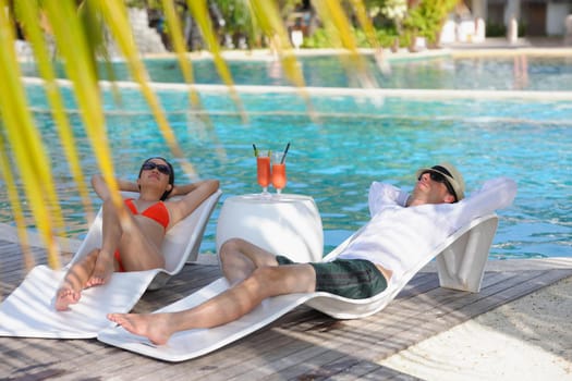 happy young couple relax and take fresh drink at summer vacation on swimmin pool