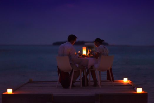 romantic couple  in love have dinner in outdoor restaurant with candles with sea in background