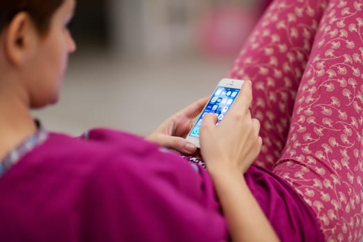 young woman in sleepwear using mobile phone while lying at home