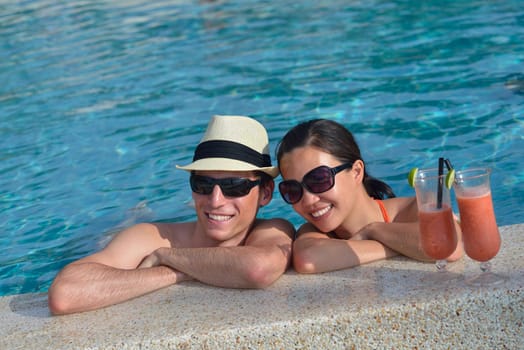 happy young couple relax and take fresh drink at summer vacation on swimmin pool