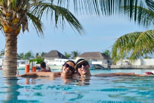 happy young couple relax and take fresh drink at summer vacation on swimmin pool