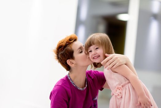 family having fun on beutiful evening at home young mother helping cute little daughter while putting on a pink dress for dancing at home