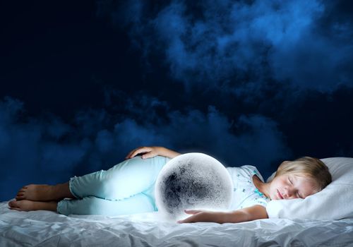 Cute girl sitting in bed and looking at moon planet
