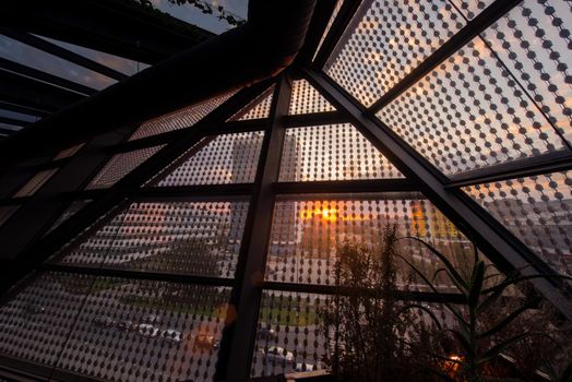 sunset or sunrise above the city through a glass roof in a modern building
