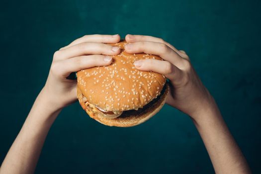 hamburger in hands close-up fast food green background. High quality photo