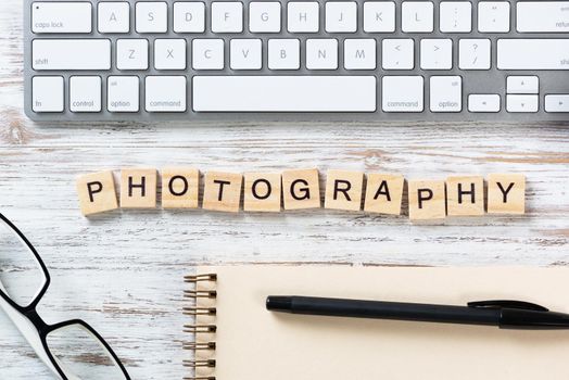 Photo studio advertising with letters on cubes. Still life of workplace with supplies. Flat lay vintage wooden desk with computer keyboard and spiral notebook. Create photography and visual content